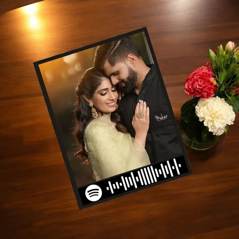 Framed photograph of a couple on a wooden surface with flowers in the background