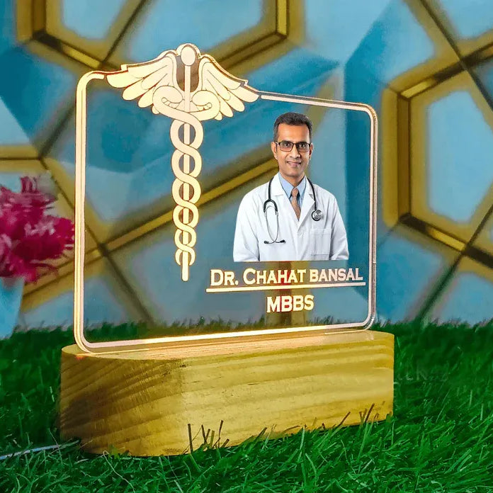 Decorative plaque with a doctor's photo and name on a grassy surface with flowers in the background