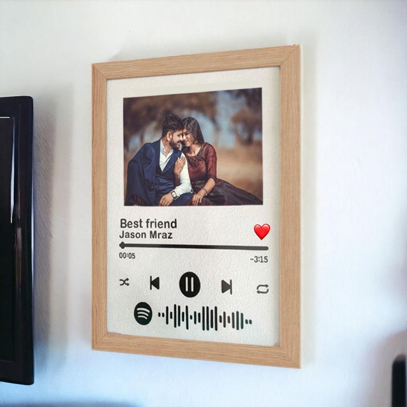 Framed artwork with a photo of two people, text, and music player interface design on a white wall.
