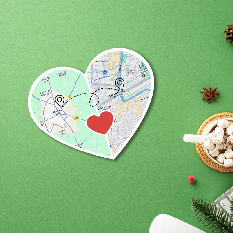 Heart-shaped map with a red heart in the center on a green background with a cup of hot chocolate and Christmas decorations.