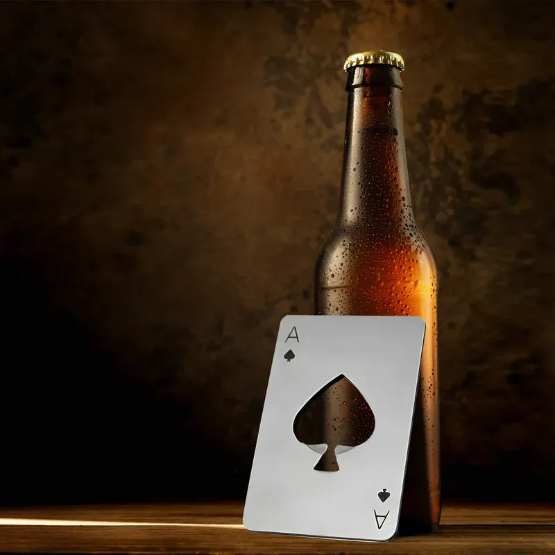 Beer bottle with a playing card shaped like an ace of spades on a wooden surface.