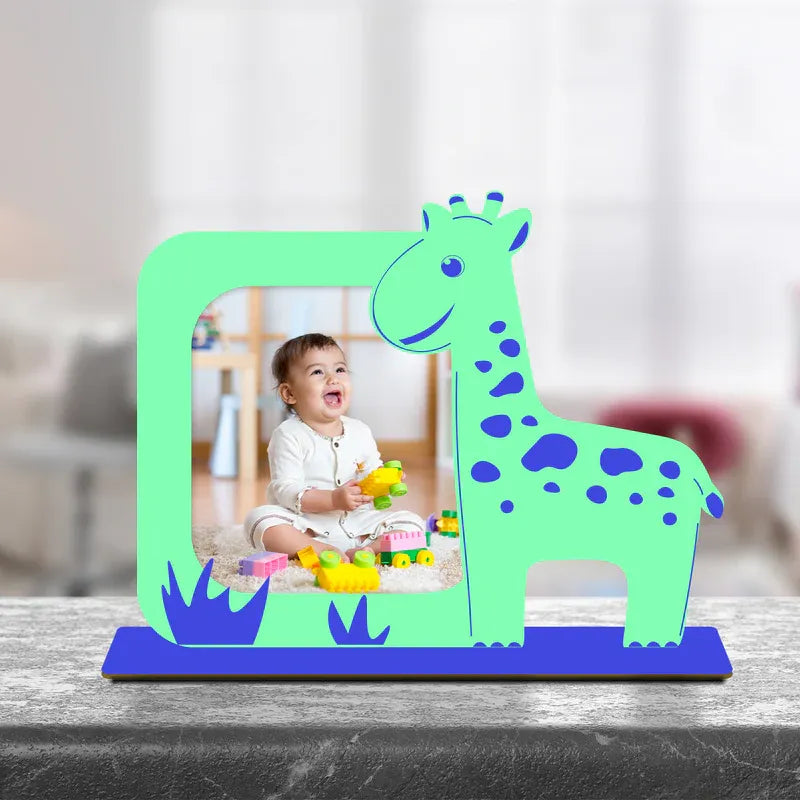 Personalised baby frame — bright green giraffe shaped acrylic photo frame with blue spots grass detail and smiling baby photo displayed on marble surface, unique giraffe baby photo frame gift India from Zingy Gifts.