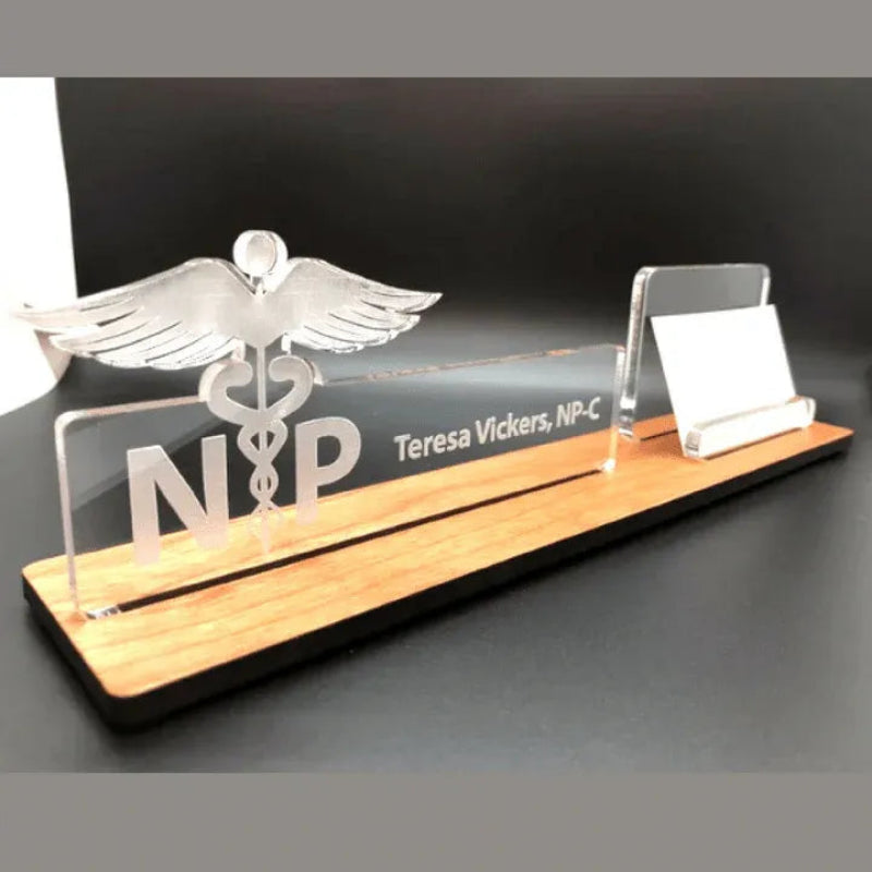A nameplate with 'N.P.' and a caduceus symbol on a wooden base with a black background.