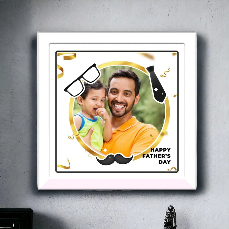 Framed picture of a man and child with decorative elements and 'Happy Father's Day' text on a gray wall.