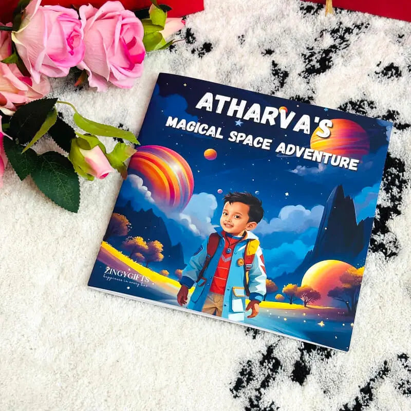 A custom children's picture book titled 'ATHARVA'S MAGICAL SPACE ADVENTURE' by ZingyGirls, featuring a colorful space-themed cover illustration with a child in a space suit. The book is styled on a white textured blanket next to pink roses.