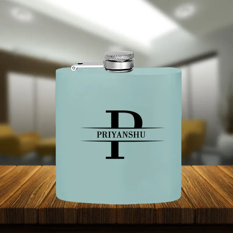 A custom hip flask in blue color with a silver cap and the engraved initial 'P' along with the text 'PRIYANSHU' on the front.