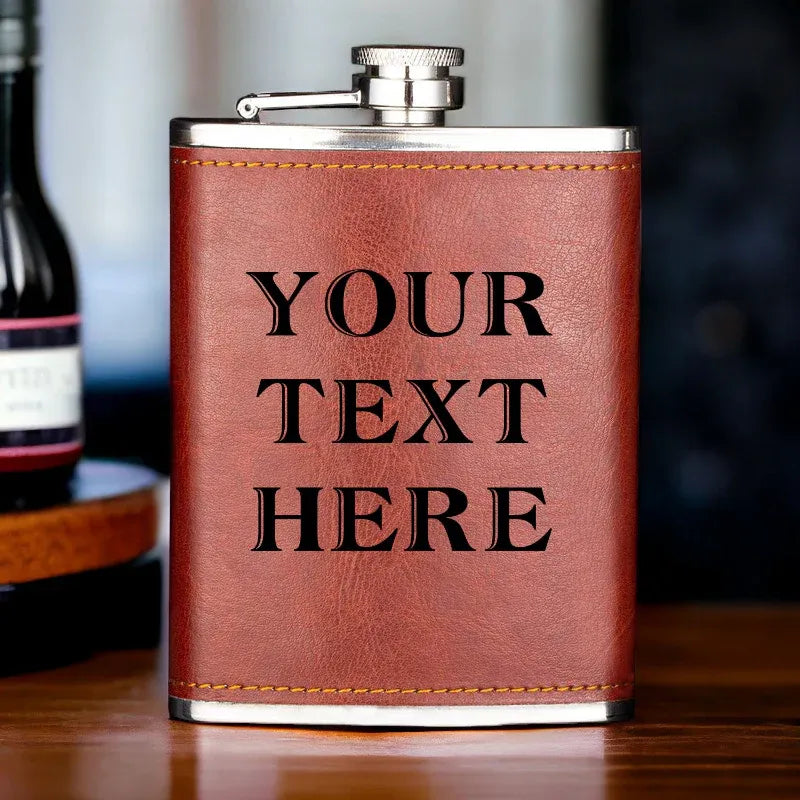 Brown leather flask with 'YOUR TEXT HERE' engraving on a wooden surface.