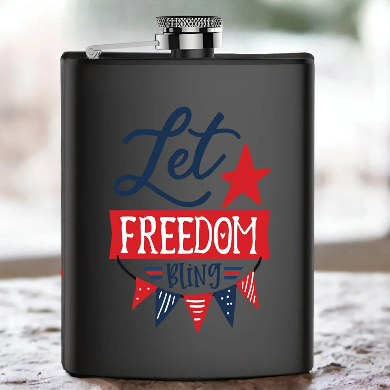 Black flask with 'Let Freedom Bling' text and patriotic design on a wooden surface.