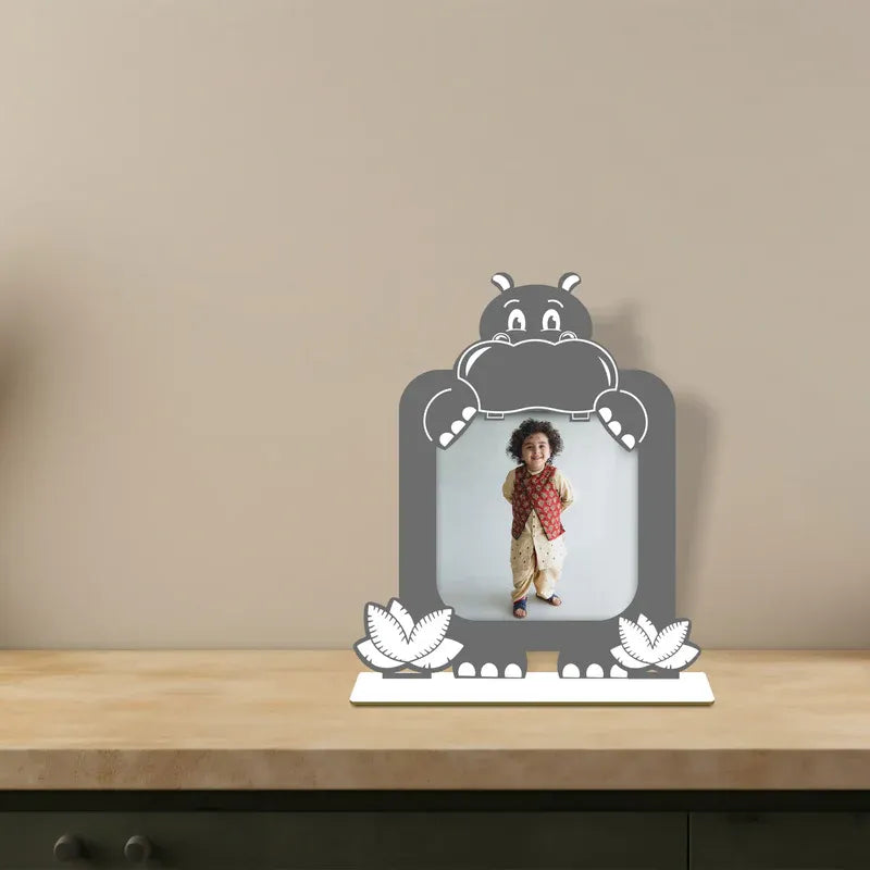 Decorative photo frame with a cartoon hippo design on a wooden surface.