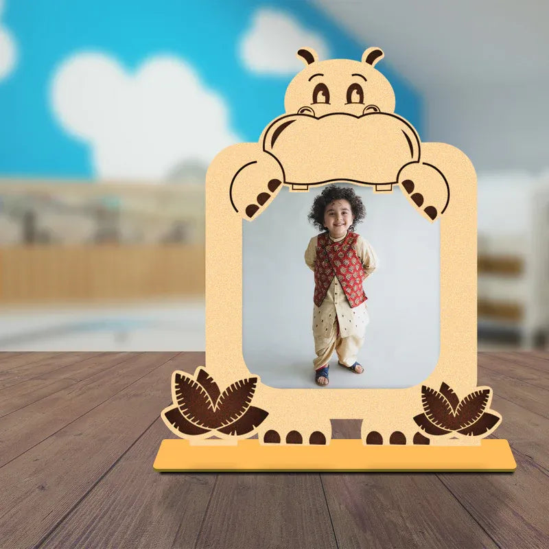 Wooden hippo baby photo frame with a child’s picture, placed on a surface with a softly blurred indoor home background.