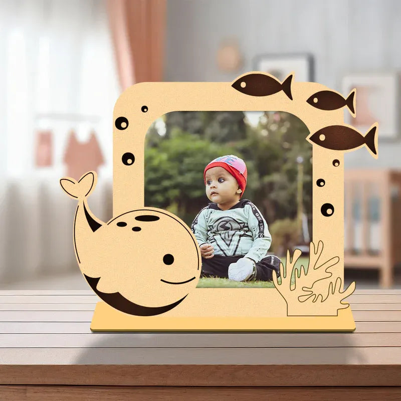 Wooden picture frame shaped like a whale with a child's photo inside, on a wooden surface.
