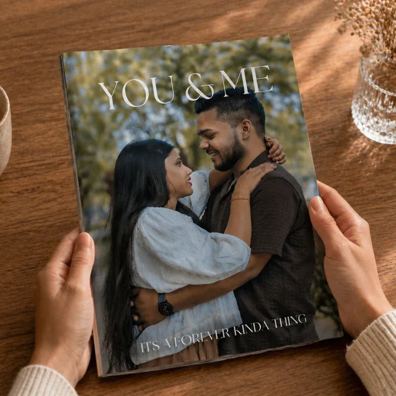 Personalized couple magazine book titled 'You & Me' held by a person on a wooden table with a couple on the cover.