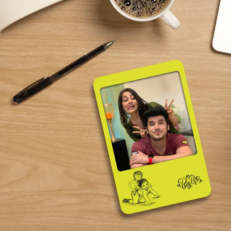 Personalized fridge magnet with a sibling's picture on a wooden surface with a pen and coffee cup.
