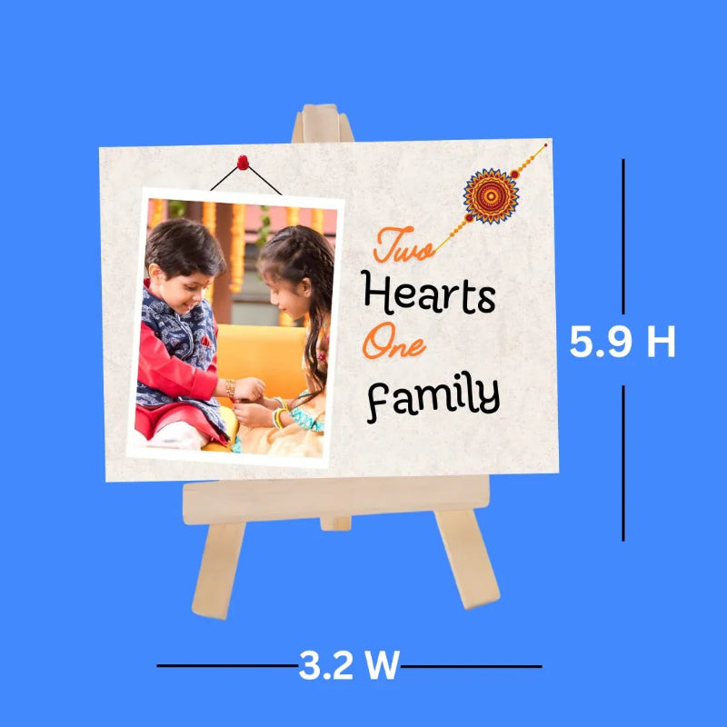 A personalized miniature wooden photo easel on a solid blue background, showing a sample print with the text 'Two Hearts One Family' and a photo of two children. White dimension lines indicate 5.