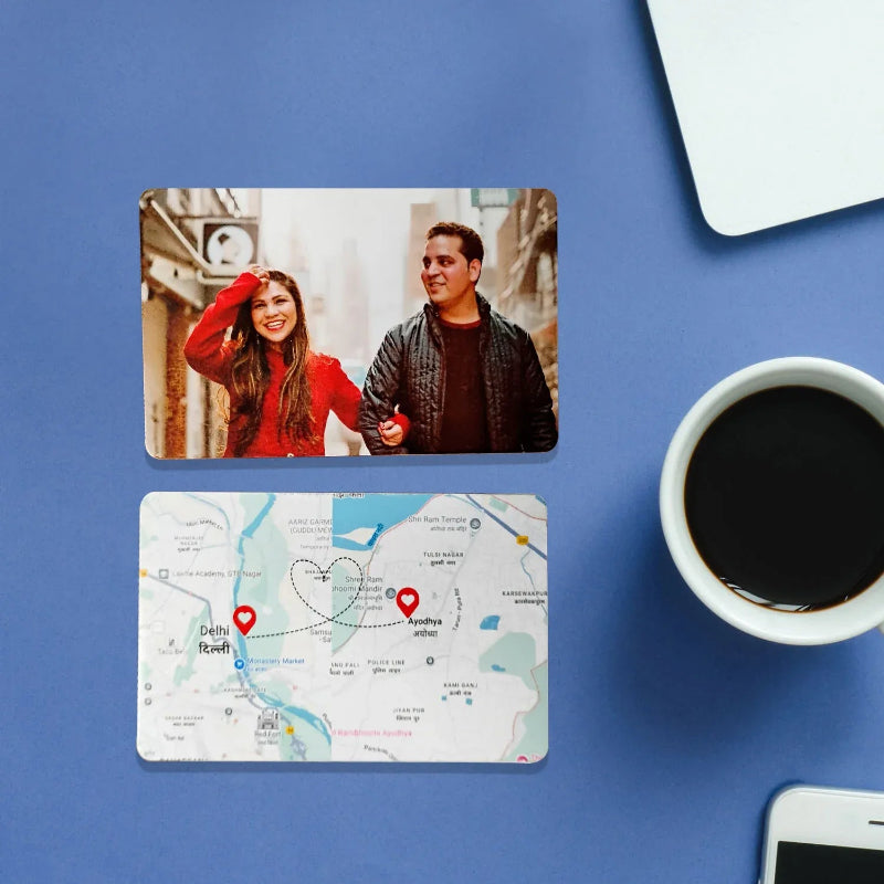Two cards with a photo of a couple and a map design on a blue surface with a cup of coffee and phone.