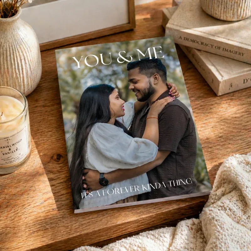 Book titled 'YOU & ME' with a couple on the cover, placed on a wooden surface with a candle and books in the background.