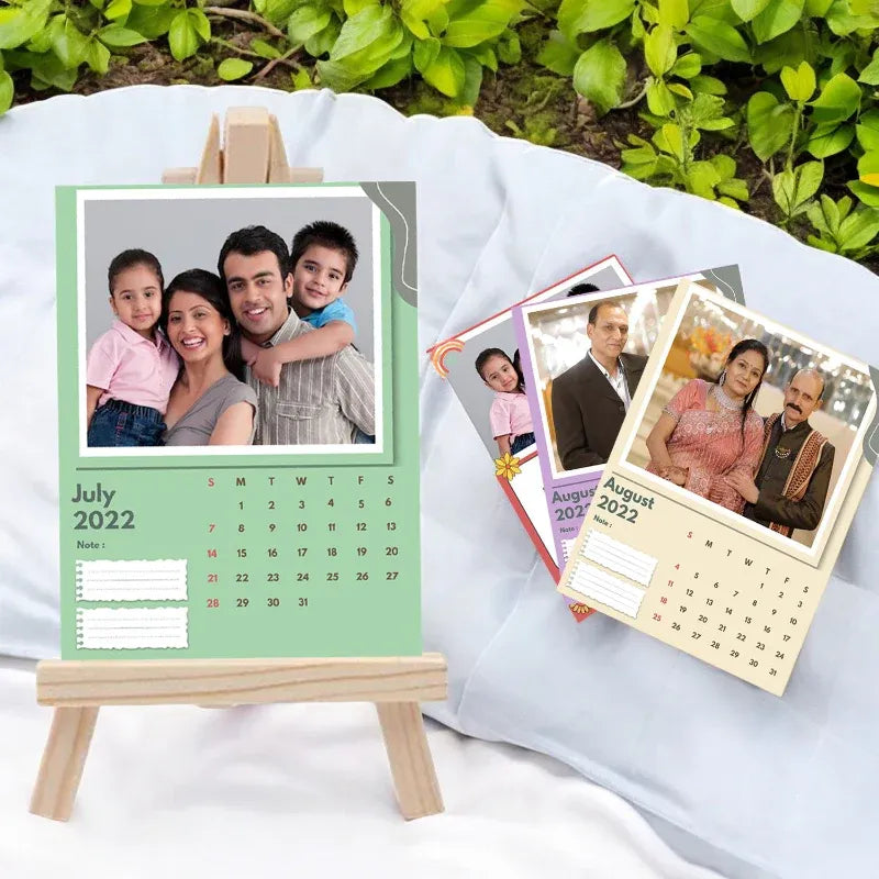 Personalized photo calendar with family portraits on a white surface with greenery in the background
