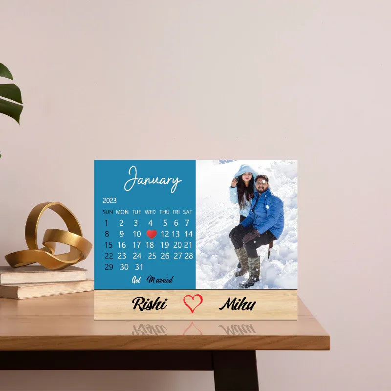 Personalized calendar with a photo of a couple on a snowy day, placed on a wooden surface.