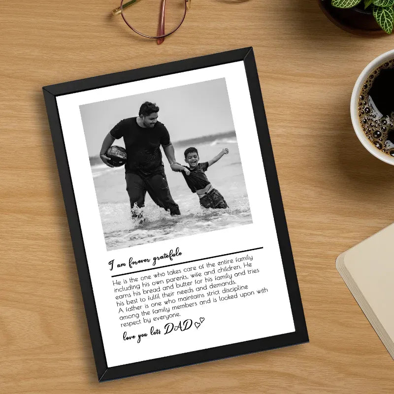 Framed photo of a man and child on a beach with a heartfelt message on a wooden surface.