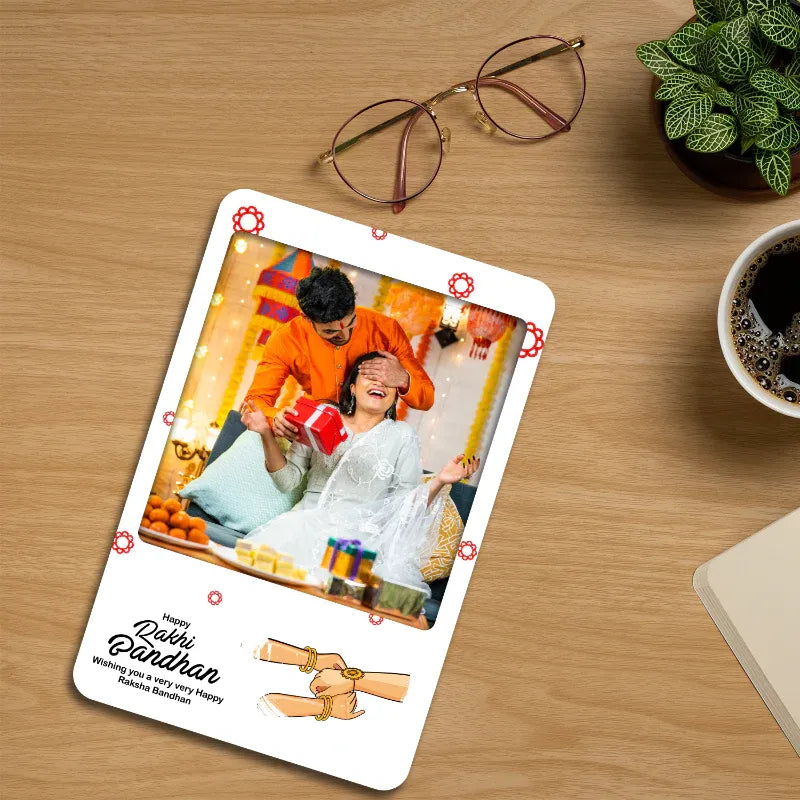 photo magnet with a brother sister photo celebrating rakhi on a wooden table with glasses and coffee.