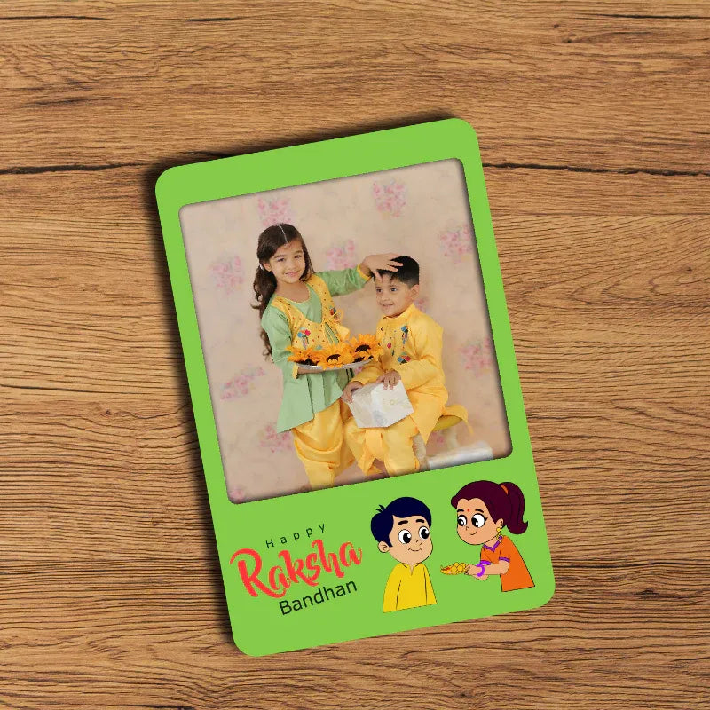 fridge magnet with two children on a wooden surface, featuring 'Happy Raksha Bandhan' text.