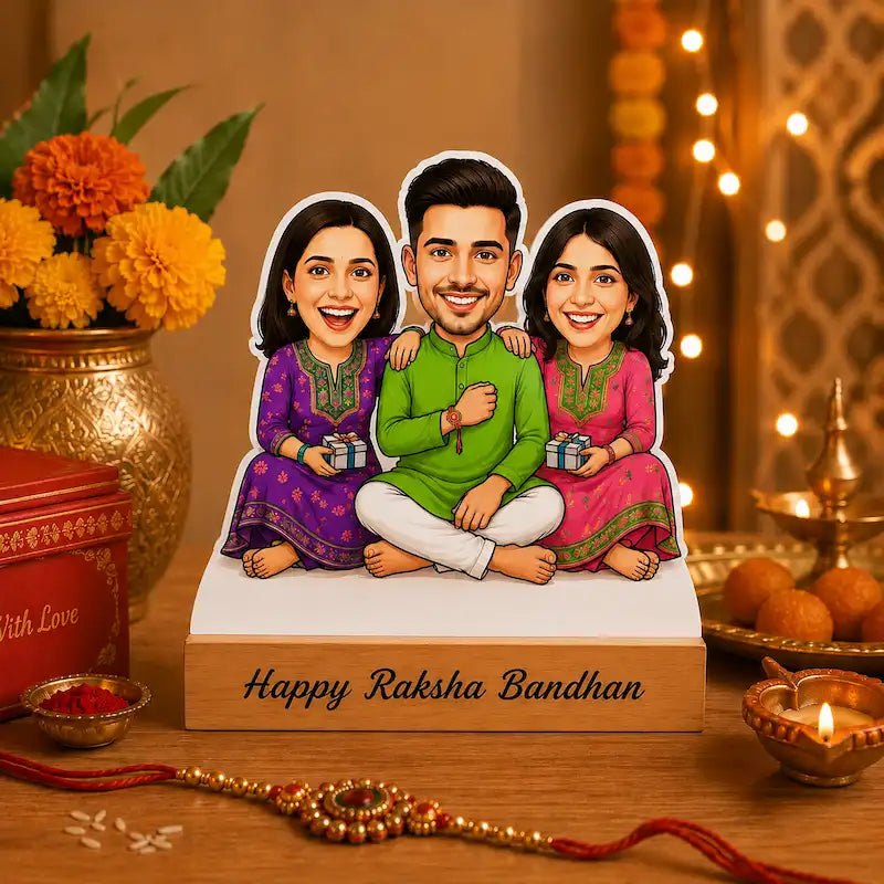 A custom cartoon family cutout displayed on a wooden base with the text 'Happy Raksha Bandhan' printed on it. The illustration shows a father and two children dressed in festive traditional Indian clothing, sitting together.