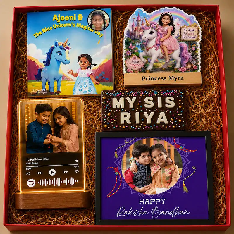 A personalized gift box set containing custom children's items: a book titled 'Aajoni & The Blue Unicorn's Magic Day', a 'Princess Myra' plaque, a Spotify-player-style wooden music box with custom audio, a 'MY SIS RIYA' glitter sign, and a purple framed 'Happy Raksha Bandhan' photo frame, all arranged in brown shredded paper inside a red box.