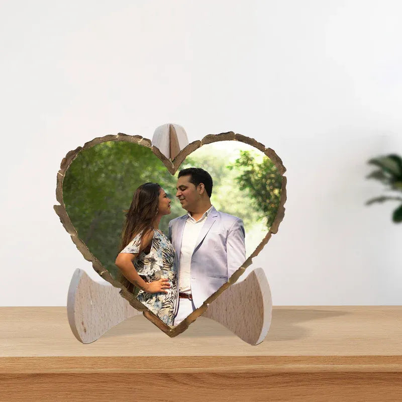 Heart-shaped wooden photo display with a couple's photo on a wooden surface.
