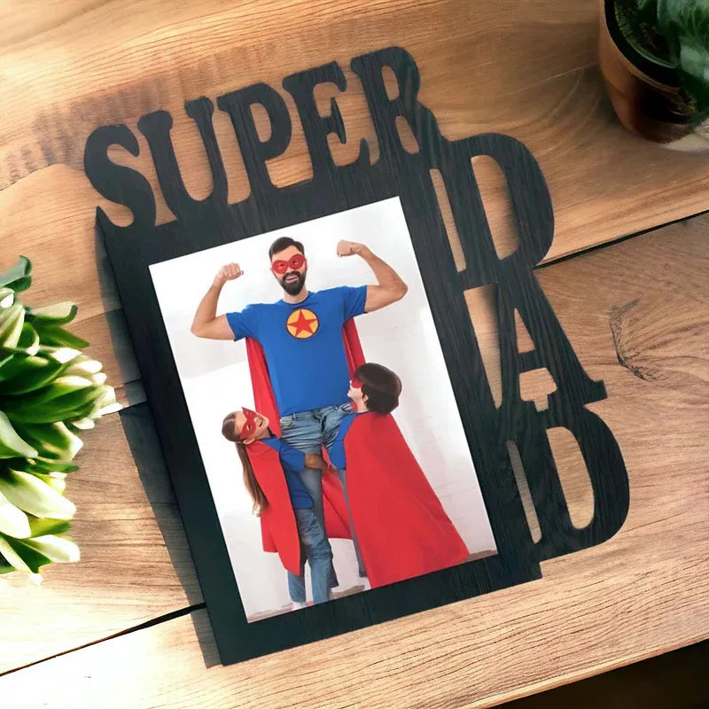 Decorative photo frame with 'SUPER DAD' text on a wooden surface.