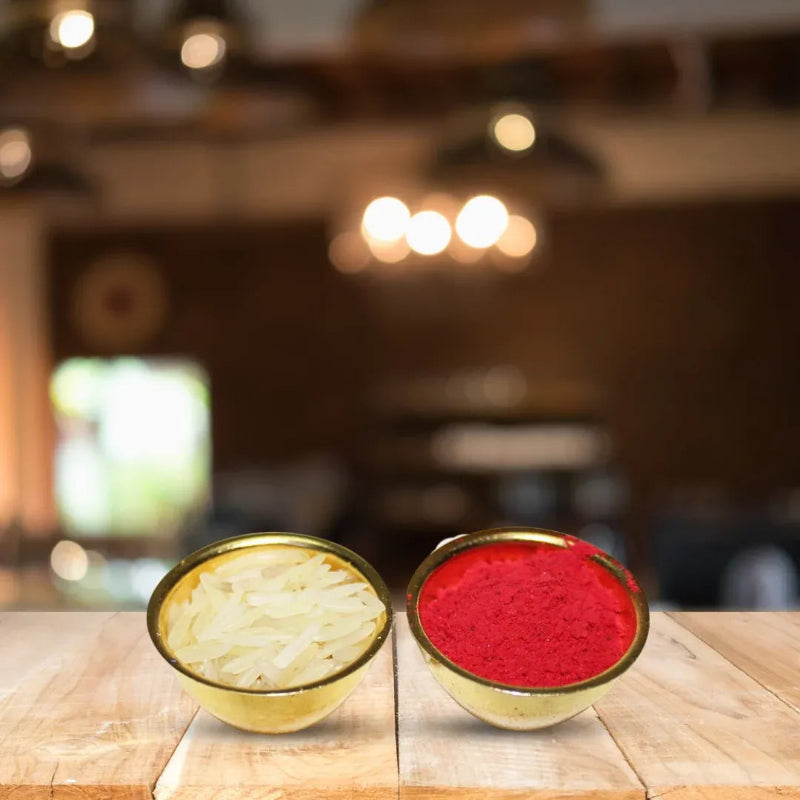 Two small bowls filled with colorful powder or shredded material, one pale yellow and one bright red, placed on a wooden table with a blurred indoor background.