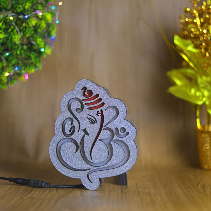 Decorative lamp with Ganesha design on a wooden surface with blurred decorative items in the background.