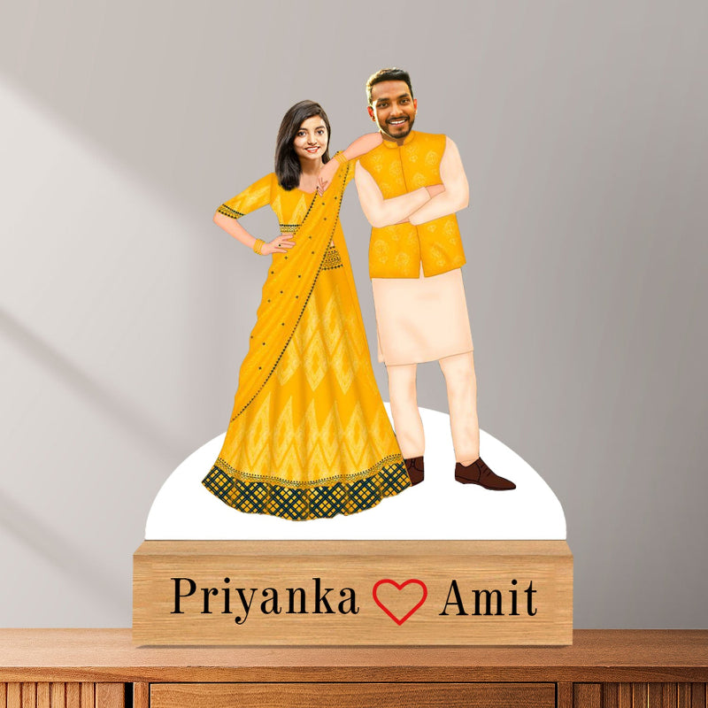 Figurine of a couple in traditional attire with 'Priyanka' and 'Amit' on a wooden base.