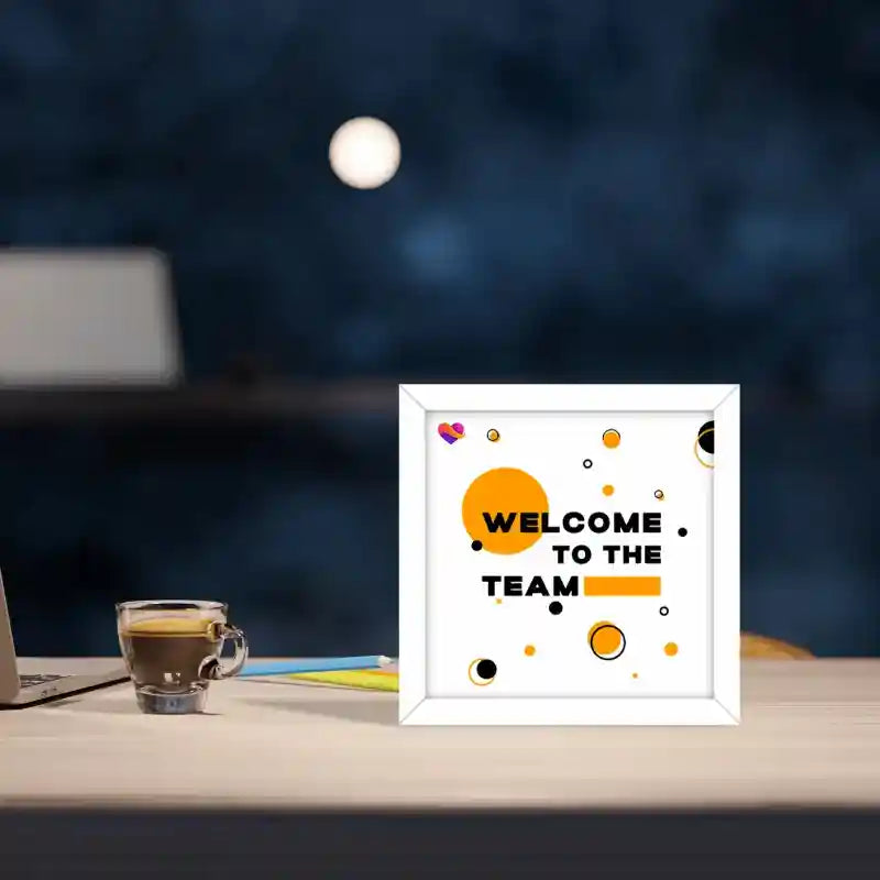 White corporate photo frame with Welcome to the Team design on a desk at night