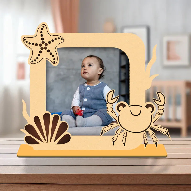 Wooden photo frame with starfish, shell, and crab designs on a blurred indoor background