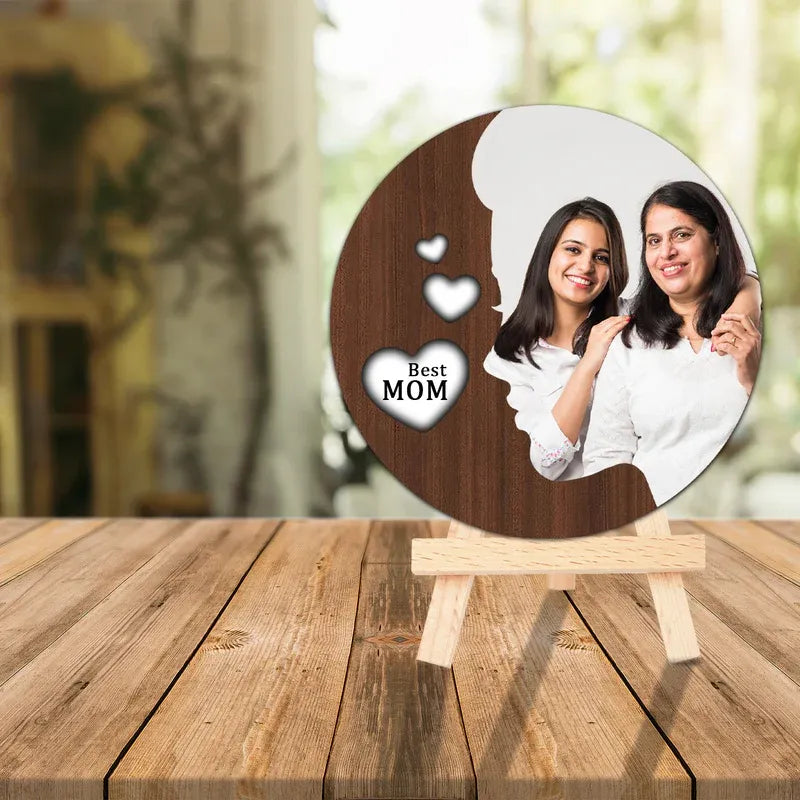 Round wooden photo frame with a cutout of two women and 'Best Mom' text on a wooden stand.